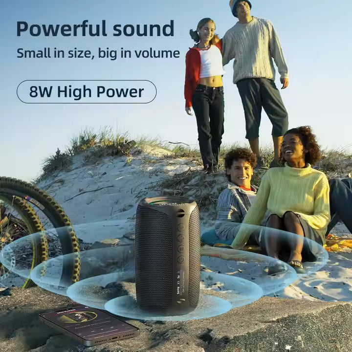 Portable speaker on a beach with people enjoying the outdoors, emphasizing powerful sound and high power.